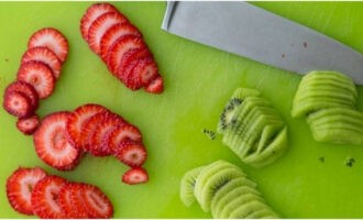 Renteu bé les fruites i baies que hàgiu escollit per al pastís i talleu-les a rodanxes fines. Hem escollit una combinació molt saborosa de maduixes i kiwi.