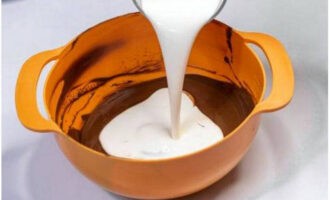 Turnați smântâna rece rece în amestecul de ciocolată. Amestecați ingredientele cu mișcări rapide.