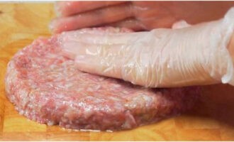 Smörj skärbrädan med vegetabilisk olja så att köttfärsen inte fastnar. Dela hela massan i 2-3 lika delar. Forma sedan platta kotletter med en diameter på 10-15 centimeter och en tjocklek på 1,2-1,5 centimeter på brädan.