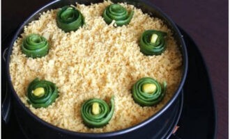 Rắc đều salad với lòng đỏ xắt nhỏ và trang trí bằng những dải ruy băng cuộn dưa chuột. Lấy món salad cua đã chuẩn bị với ngô ra khỏi nhẫn và có thể dọn ra ngay trên bàn ngày lễ.