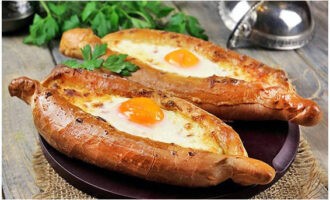 We serveren geurige Khachapuri in Adjariaanse stijl gloeiend heet op tafel en genieten ervan. Eet smakelijk! 