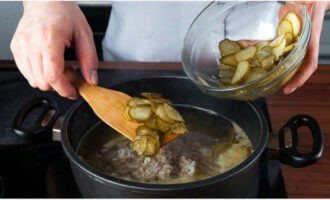 Tillsätt beredd pärlkorn och pickles här, tillsätt salt och mald peppar efter smak. Koka i 10 minuter på låg värme. Stäng sedan av elden och håll arbetsstycket under locket.