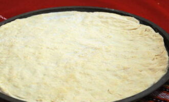 A vékony pizzatészta, mint egy pizzériában, készen áll. Nyújtsuk ki vékony alapra, és folytassuk a további előkészítést.