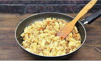 Adăugați pastele la carnea tocată cu legume, amestecați și încălziți încă câteva minute.