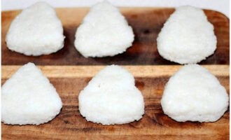 Đậy kín phần nhân bằng cơm. Chúng tôi bọc phần dưới của hình tam giác bằng nori. Nếu muốn, khoảng trống có thể được trang trí.