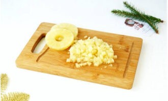 Az ananászkonzerv kifejtése és a levét lecsöpögtetése után a gyümölcsöt kockákra vágjuk. Hagyjon néhány gyűrűt a díszítéshez.