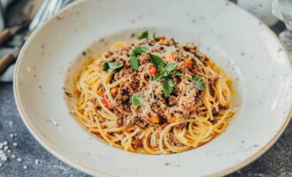 Klassisk Bolognese pasta med köttfärs i en stekpanna är klar. Servera, toppad med riven ost och örter.