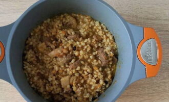 Acum adăugați terciul de orz perlat fiert la carne de vită, amestecați și fierbeți la foc mic încă 10 minute.