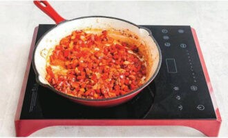Aboqueu oli vegetal en una paella calenta. Primer, sofregiu la ceba i l'all durant 5 minuts.A continuació, afegiu-hi els pebrots calents i dolços i continueu la cocció durant 7 minuts, remenant amb una espàtula. Afegiu el pebre vermell fumat, els flocs de xili i la pasta de tomàquet i deixeu-ho coure un parell de minuts més.