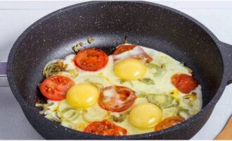 Quan les rodanxes de tomàquet estiguin fregides pels dos costats i les cebes es tornen translúcides, trencar els ous de gallina. Saleu i condimenteu el plat al gust.