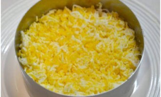 Voeg vervolgens een laag geraspte kippeneieren toe, zout een beetje en bestrijk met mayonaise.