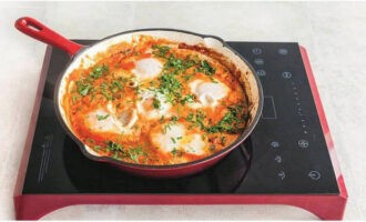 Feu forats al sofregit de tomàquet segons el nombre d'ous, trencar-hi els ous. Cuini el shakshuka fins que les clares estiguin ben cuajades.
