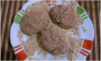 Doe het broodkruim op een bord. Gebruik je handen of een eetlepel om het varkensgehakt op te scheppen, vorm er ronde schnitzels van en rol ze door paneermeel.
