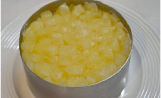 Leg de gehakte ananas uit blik op de eierlaag en bedek deze met mayonaise.