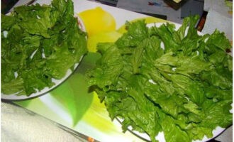 Du kan gå vidare till att sätta ihop Caesarsalladen. Lägg salladsblad på en platt tallrik.