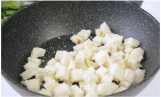 Hur förbereder man en enkel och god sallad med röd fisk? Efter att ha skurit av skorporna från brödet, skär fruktköttet i kuber av samma storlek och häll i en torr, het stekpanna.