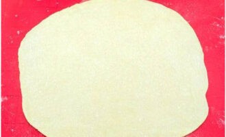 Låt oss gå vidare till att forma desserten: kavla ut ett segment av deg till en rund kaka, cirka 30-32 centimeter i diameter.