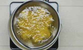 Lägg den panerade kycklingen i ett enda lager i en stor sil. Sänk ner silen i kokande olja. Stek bitarna i 8 minuter. Om ett speciellt nät finns tillgängligt använder vi det.