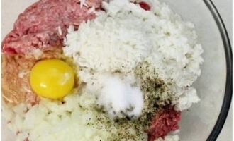 Hur lagar man hackade igelkottar med ris och sås i ugnen? Förbered din mat och sätt på ugnen. Skölj risflingorna med kokande vatten och låt rinna av i ett durkslag. I en stor skål, kombinera köttfärs, ris, två hackade lökar, ett kycklingägg, kokt vatten, salt och mald peppar.