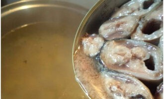 Öppna burken med konserverad fisk och lägg allt innehåll i pannan.