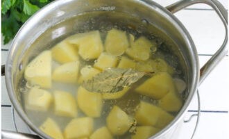 วางกระทะที่มีน้ำซุปไก่ลงบนกองไฟ ใส่มันฝรั่งลงไป และปรุงเป็นเวลา 10 นาที