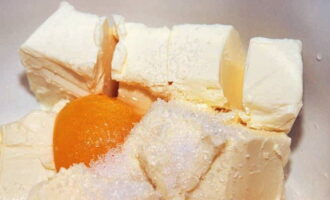 Làm thế nào để nấu bánh shortbread trong lò? Trong một bát sâu, kết hợp các miếng bơ, đường và vanillin. Chúng tôi cũng đập trứng gà ở đây.
