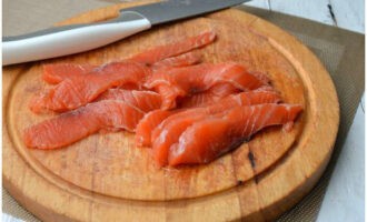 Talleu a rodanxes fines un tros de peix vermell.