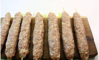 Chúng tôi làm ướt những xiên gỗ trong nước và làm xúc xích từ thịt băm đã chuẩn bị sẵn trên mỗi xiên.