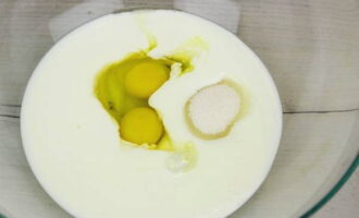 Acum puteți face aluatul pentru plăcinte. Turnați chefir cald într-un castron; îl puteți lua de orice conținut de grăsime. Rupeți ouăle de pui în chefir, adăugați sare și zahăr și turnați uleiul vegetal. Amesteca totul bine cu o furculita.
