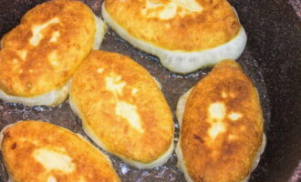 Când toate plăcintele sunt gata, puneți tigaia pe foc. Când se încălzește bine, se toarnă ulei vegetal în așa cantitate încât plăcintele să fie scufundate pe jumătate. Puneți plăcintele cu cusătura în jos și prăjiți la foc mediu până devin aurii. Acest lucru va dura aproximativ 2-3 minute pe fiecare parte. 