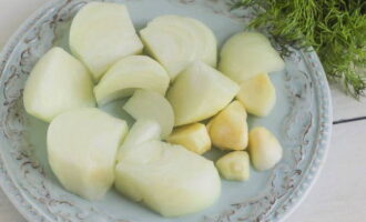 Bóc vỏ hành và tỏi. Chúng tôi cắt hành tây thành miếng.
