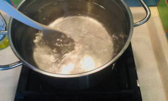 Aboqueu aigua a la paella i col·loqueu el recipient al foc. L'aigua en què es bullirà l'ou ha d'estar a punt de bullir. Quan l'aigua comenci a bullir, feu servir una cullera per remenar-la formant un cercle per formar un embut al centre.