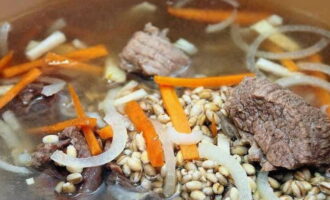 Colar el brou acabat i tornar-hi la carn. També afegim llorer i grans de pebre a la sopa. Afegiu l'ordi perlat rentat i deixeu-ho coure durant 15 minuts més. A continuació, afegiu-hi les verdures i continueu cuinant la sopa a foc lent.