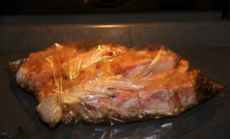 Fixați o margine a manșonului de copt, puneți coastele marinate în interior și așezați-le lejer acolo. Legați a doua margine a mânecii și puneți pachetul pe tava de copt. Pentru a permite aburului să scape, faceți mai multe perforații în partea de sus a mânecii.