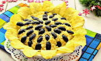 Gupitin ang mga olibo sa kalahating pahaba. Ilagay ang mga ito sa ibabaw ng salad. Ilagay ang mga chips sa gilid, sila ay kumikilos bilang mga petals. Ang sunflower salad na may mga chips ay handa na, ihain ito nang malamig. Bon appetit!