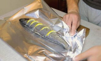 Spreid een groot vel voedselfolie op tafel, vet het in met plantaardige olie en plaats het voorbereide karkas van roze zalm in het midden. Wikkel de vis stevig in folie, zodat er geen gaten meer in zitten. Doe hetzelfde met de tweede vis. Bewaar de roze zalm vóór het bakken ongeveer een half uur in de koelkast, zodat hij goed gemarineerd is met kruiden.
