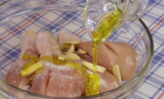 Thêm tỏi băm nhỏ vào đùi gà đã chuẩn bị, cũng như muối (điều chỉnh theo khẩu vị) và đổ dầu ô liu.