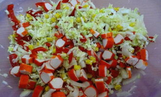 Krabsticks, in plakjes gesneden, worden aan de salade toegevoegd.