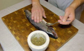 Wrijf de bereide marinade van binnen en van buiten over de karkassen van roze zalm en bedek ook elke snee.