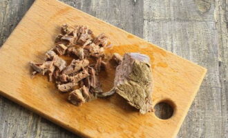 Lấy thịt bò luộc ra khỏi xương và cắt thành từng miếng nhỏ. Cho thịt và xúc xích vào nước dùng, khuấy đều và đun nhỏ lửa trong 5 phút.